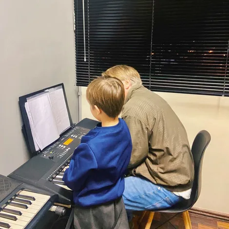 Professor orientando aluno no piano – leitura e repertório.
