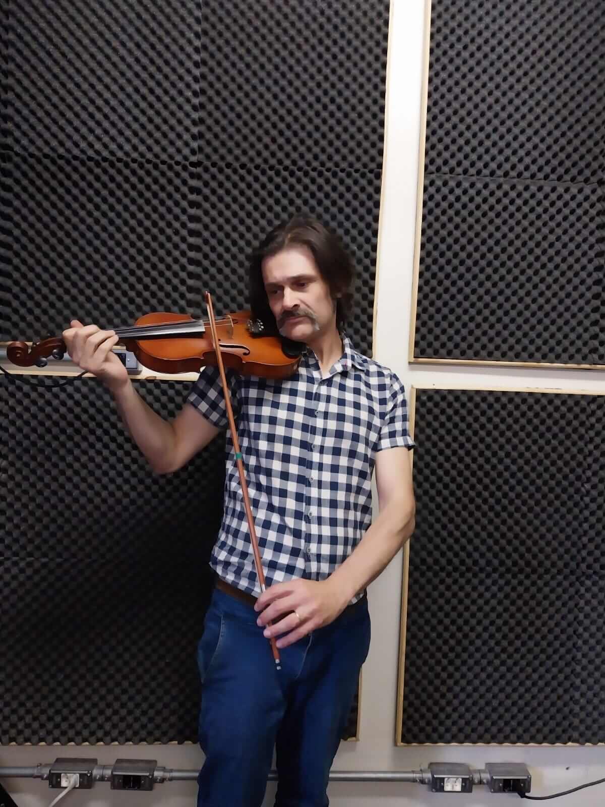 Professor de violino tocando em sala tratada acusticamente, aulas presenciais na Vibrato em Porto Alegre.