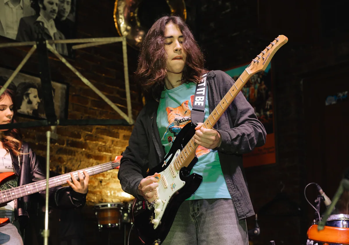 Aluno tocando guitarra em apresentação da Vibrato em Porto Alegre